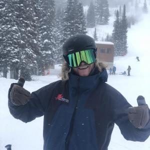 Snowboarder with green goggles giving thumbs up