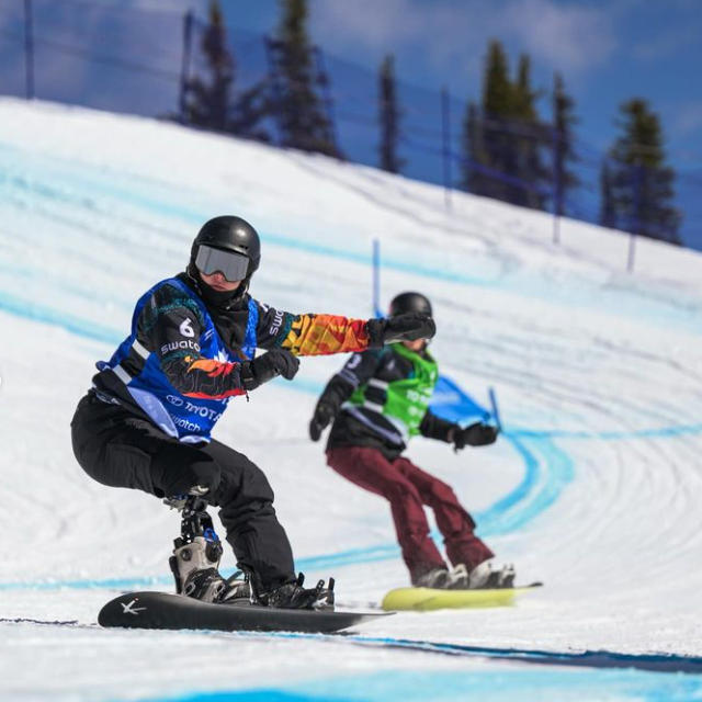 Two snowboarders racing on snowy slope