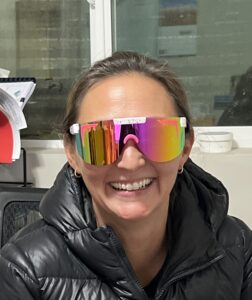 Smiling person wearing mirrored rainbow sunglasses