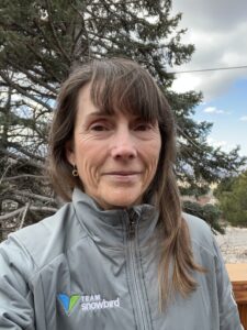 Woman in gray jacket outdoors by tree